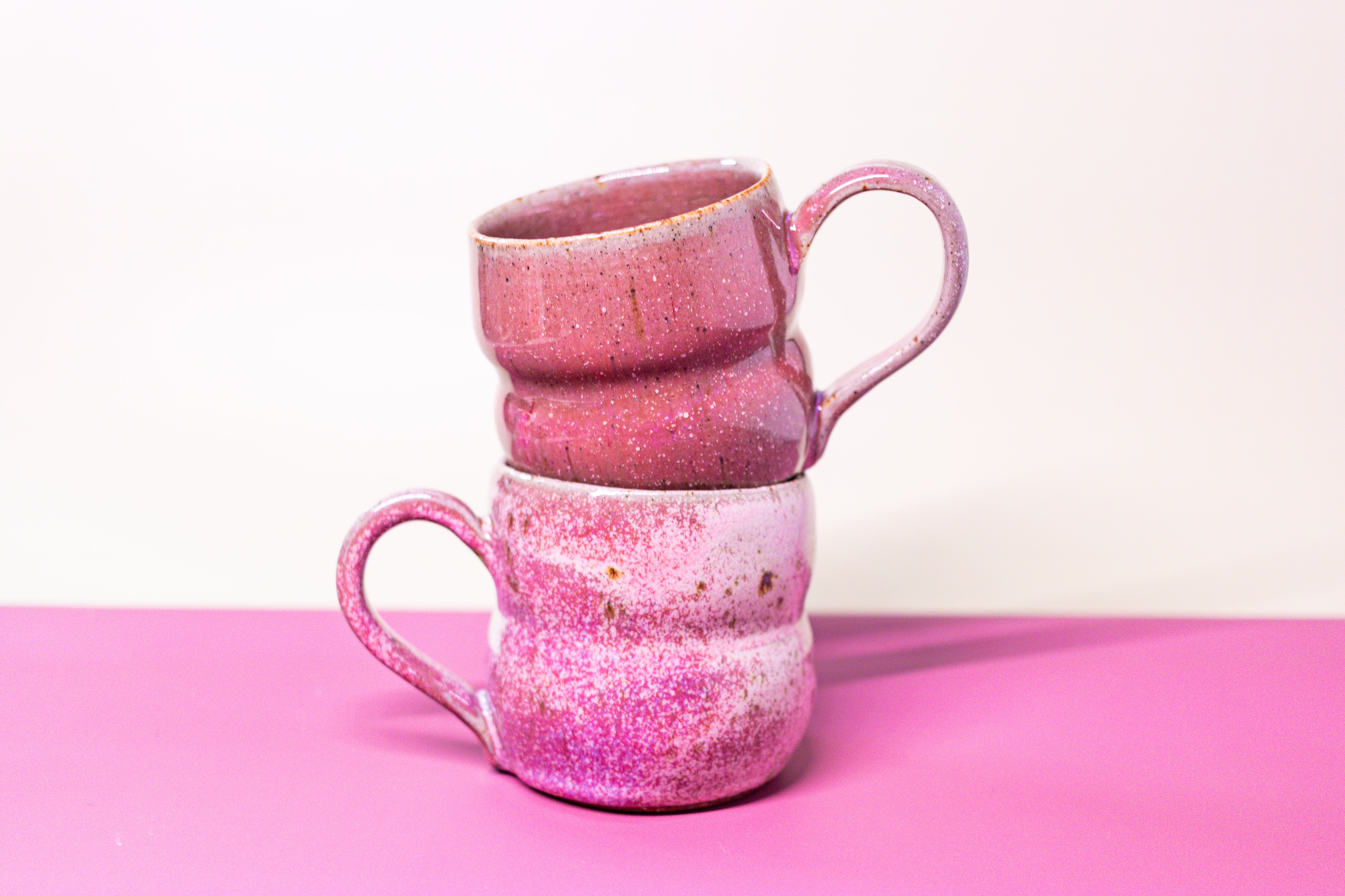 Stack of pink ceramic mugs on a pink background