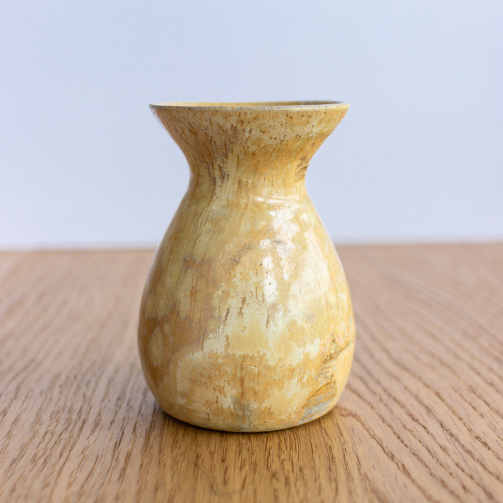 Decorative yellow crystalline bud vase on a wooden surface.