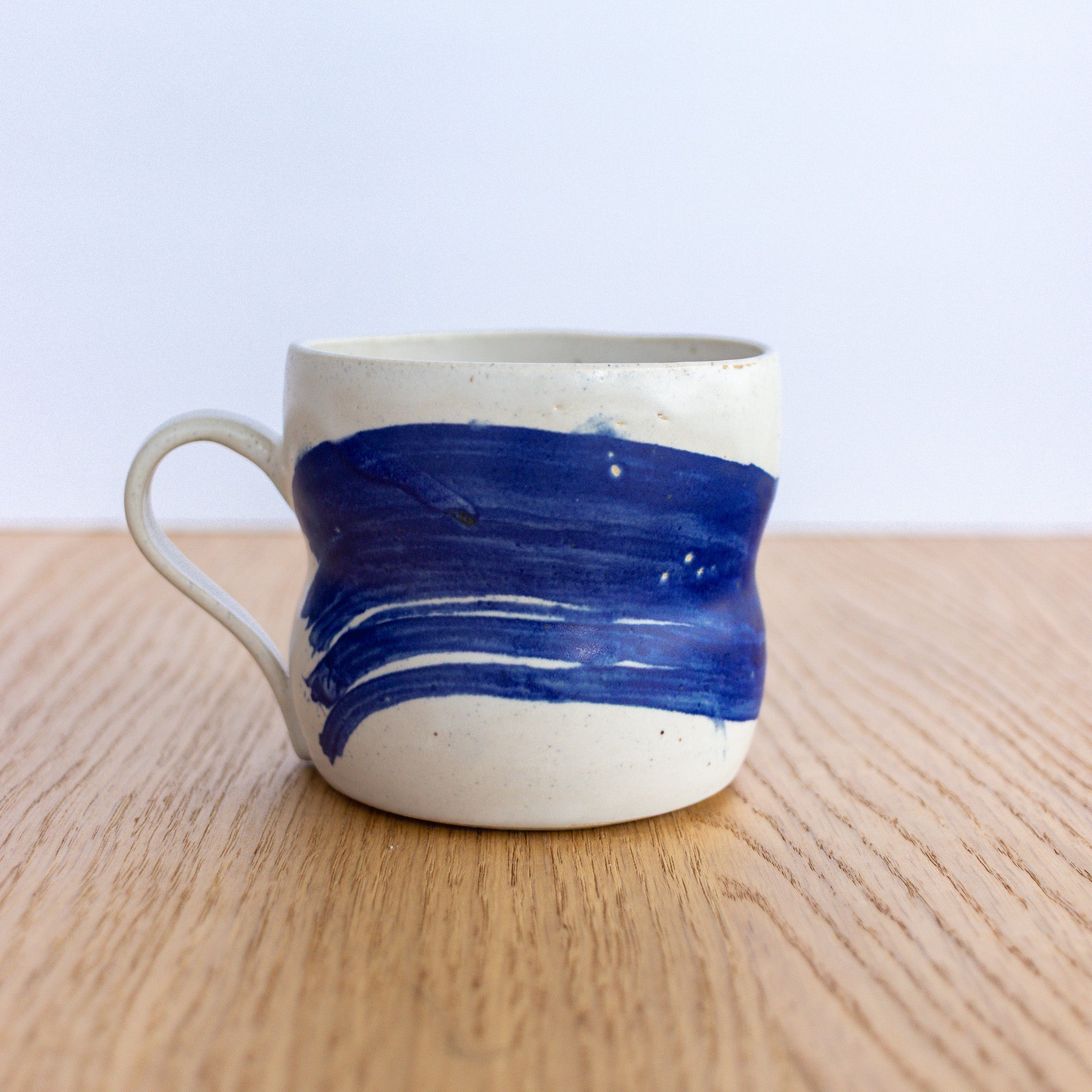 Ceramic mug with blue accent on a wooden surface